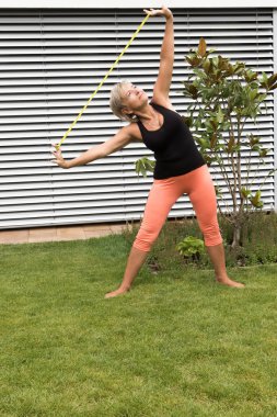 Üst düzey sarışın kadının elinde seyir ruber ile egzersiz yapması. Dikey olarak