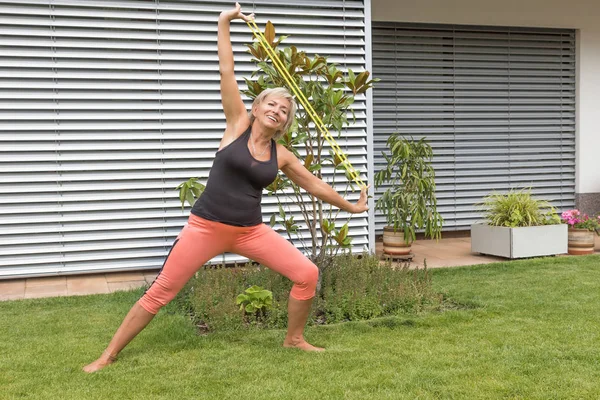 Bahçede açık kamera bakarak bir lastik ile ona yaptığını mutlu sarışın kadın kıdemli uzanır. Yatay olarak. 