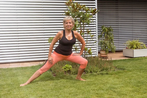 Ona yaptığını çekici sarışın kadın kıdemli bahçede açık kamera bakarak uzanır. Yatay olarak. 