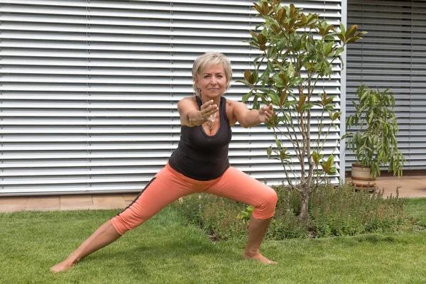 Ona yaptığını onun ön kolda çekici üst düzey sarışın kadın bahçede açık kamera bakarak uzanır. Yatay olarak. 