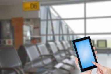 Turist tablet mavi ekranla metniniz için hazır dokunmadan eller. Kasıtlı olarak bulanık bir boş Havaalanı terminal içinde arka planda görüntüsüdür. Tüm potansiyel markalar kaldırılır.