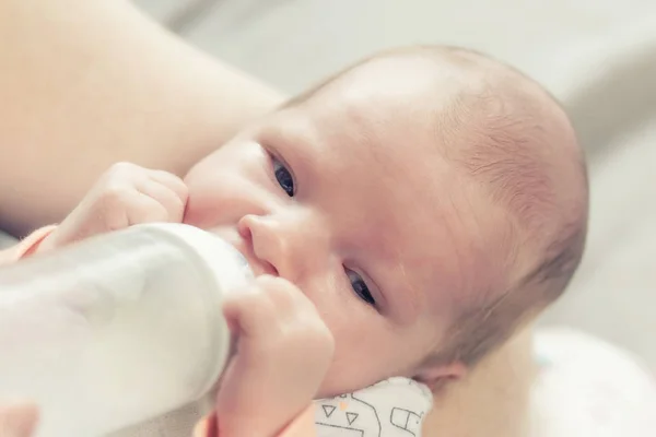 Cute newborn boy is drinking milk from bottle — Stock Photo, Image