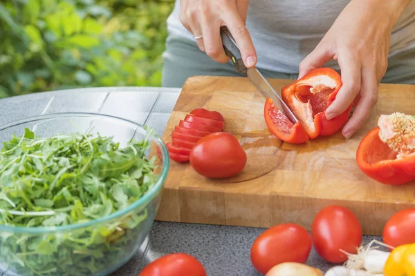 Cortando uma pimenta vermelha em uma tábua de madeira closeup — Fotografia de Stock