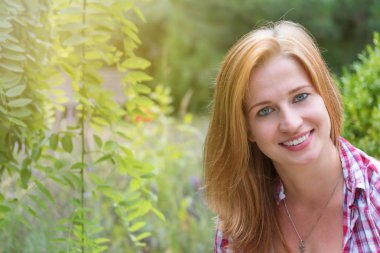 Bahçede gülümseyen genç kadının portresi