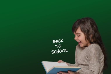 Gülen, uzun saçlı, bronz tenli küçük kız elinde bir kitap tutuyor. Üzerinde 