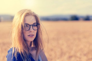 Dışarıda gözlüklü genç bir kadın poz veriyor. Eski bir fotoğraf olarak düzenlendi.