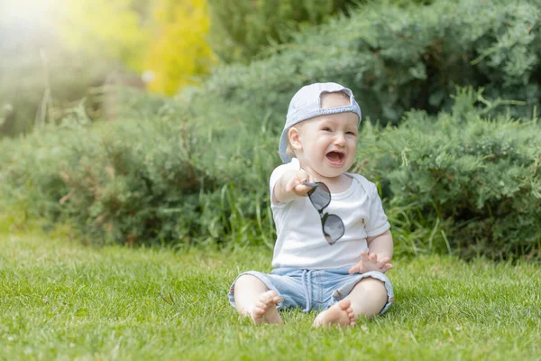 Küçük Bebek Ağlıyor Elinde Güneş Gözlüğü Bahçede Oturuyor — Stok fotoğraf