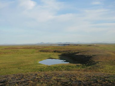 Tundra manzara. Güneş ışınları deldi yeşil otlar ile mayınları ve bir dağ gölü ile dekore edilmiş dağ hugs bulut kalın gün.