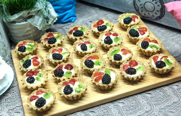Çok lezzetli tartlets krem peynir ve ahşap tahta üzerinde taze çilek ile.