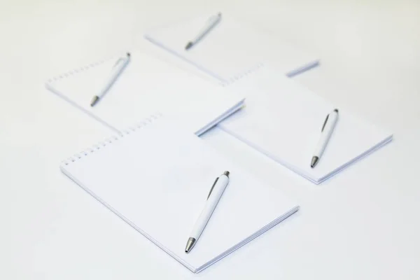Four paper notepads with pens on white background. empty copy space. Mockup.