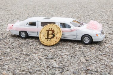 Altın sikke Bitcoin closeup model uzun beyaz lüks sedan araba asfalt zemin üzerine yakınındaki.