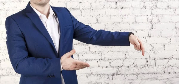 Açılan el ile giyen klasik mavi takım işaret eden bir iş adamı. Yüz, beyaz tuğla arka plan, yatay banner.