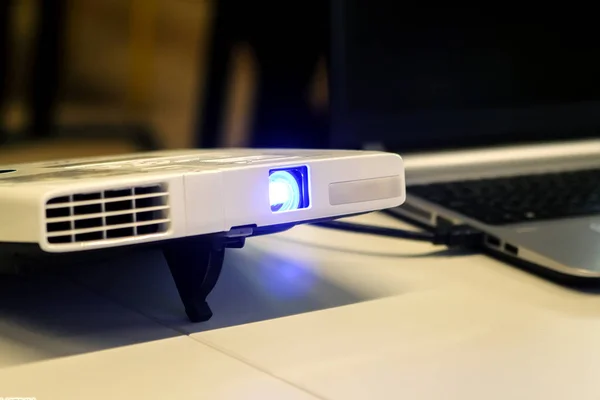 Sunu sırasında açık mavi ışın ile masa üstünde laptop ile projektör.