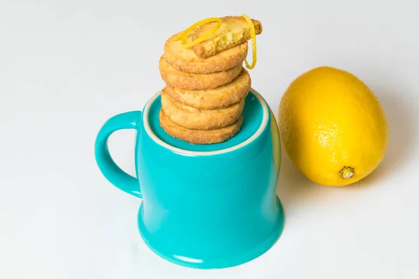 Beyaz arka plan üzerinde taze limon yakınındaki mavi Kupası kazıklı ev yapımı limonlu kurabiyeler. Portre, izole