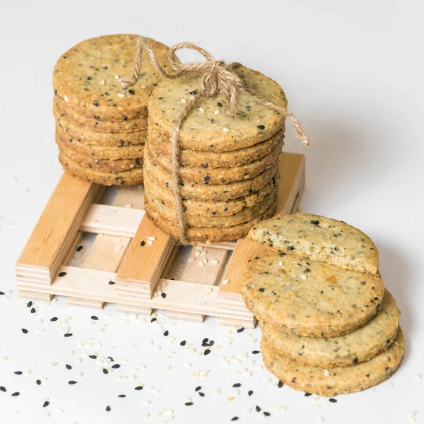 Beyaz arka plan üzerinde izole rustik sicim ile susam kurabiye kazık. Kare resim