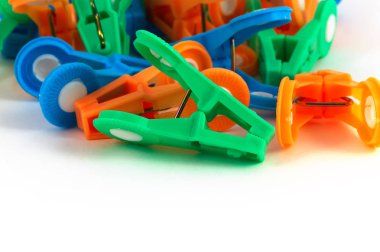 Birkaç plastik clothespins, beyaz bir arka plan ile ön planda yeşil bir clothespin üzerinde rasgele bir şeklinde ortaya koydu.