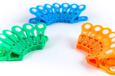 Beyaz bir arka plan üzerinde gruplar halinde düzenlenmiş yeşil, mavi, turuncu ev clothespins.