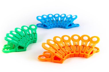 Plastik clothespins mavi, turuncu, yeşil beyaz zemin üzerinde üç grupları.