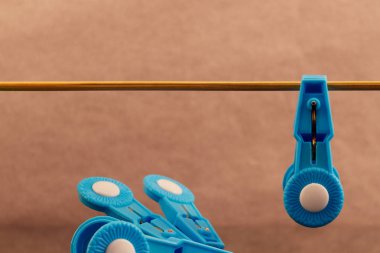 Clothespin mavi plastik sol yanındaki tahta bir sopa üzerinde asılı olan birkaç mavi elbise mandal.