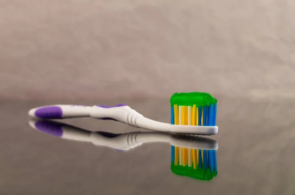 Одна Зубная Щетка Зеленой Зубной Пастой Сером Абстрактном Фоне Отражением — стоковое фото