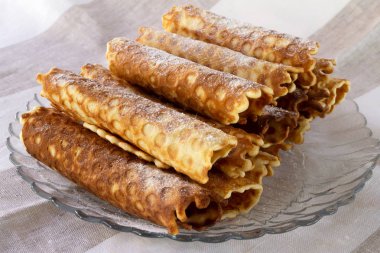 Ev yapımı hamur yuvarlak rulo bir cam tabakta pudra şekeri serpilir.