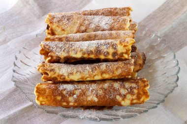 Bir cam tabakta pudra şekeri serpilir kısa hamur yapılmış gözleme.