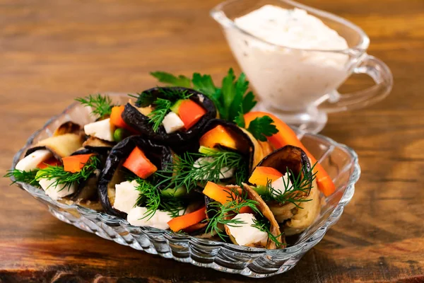 Yumuşak peynir, dereotu ve yanındaki ekşi krema ile saplı bir cam kase dilimlenmiş tatlı biber patlıcan ve sebze rulo.