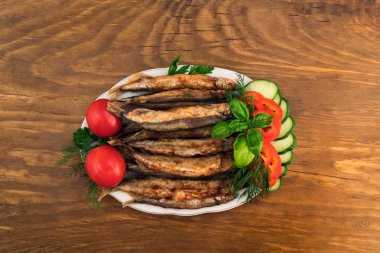 Küçük balık, kırmızı bütün domates ile bir porselen tabakta yağda kızartılmış dilim biber ve salatalık, dal dereotu, maydanoz ve fesleğen yaprakları.