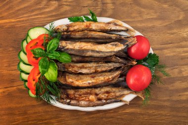 Kızarmış capelin, domates, salatalık, biber, dereotu, maydanoz ve fesleğen dilimlenmiş dilim ile bir tabakta koydu bırakır.