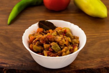 İnce kıyılmış sebzeler, havuç, tatlı biber, domates ahşap arka plan üzerinde beyaz porselen tabak içinde birlikte yağda demlenmiş meze.