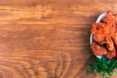 Bir fışkın maydanoz, ahşap arka plan üzerinde üstten görünüm ile bir porselen tabak içinde kırmızı bir kabuk ile hamur kızarmış balık.