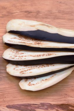 Patlıcan boyuna dilimler halinde kesin mavi deri ile ahşap bir arka plan üzerinde bir fan ile dağılın.