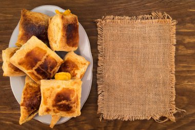 Pasta puf böreği bir bez ahşap zemin keten, en iyi görünümünün yanında bir plaka üzerinde kırmızı bir kabuk ile peynir ile doldurulmuş.