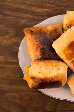 Lezzetli tatlı katmanlı peynir buns fırında pişmiş kadar altın kahverengi porselen tabakta, ahşap arka plan üzerinde üstten görünüm.