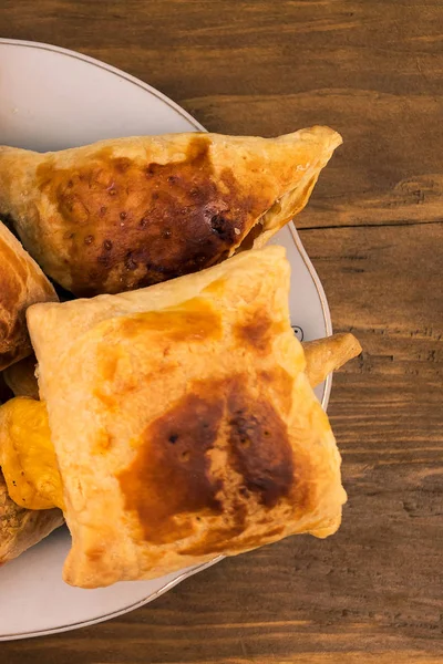 Tatlı yemek pişmiş çörekler peynir ile doldurulmuş ve elma tabakta, yukarıdan bir ahşap zemin üzerine koydu.