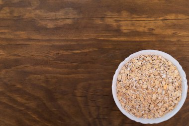 Ahşap arka plan üzerinde beyaz kase yulaf gevreği.