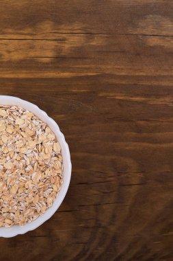 Yarım beyaz kase yulaf gevreği ahşap arka plan, üstten görünüm üzerinde dolu.