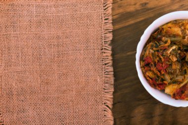 Keten kumaş peçete, üstten görünüm yakınındaki ahşap arka plan üzerinde beyaz kase Sebze Güveç.