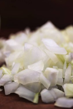 Bir ahşap masa, yakın çekim, dikey çerçeve koyu arka plan üzerinde beyaz soğan dilimlenmiş parçaları.