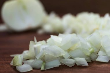 Küçük parçalar halinde bir ahşap zemin üzerine kıyılmış beyaz soğan, yakın çekim, yarım kesilmiş soğan içinde belgili tanımlık geçmiş.