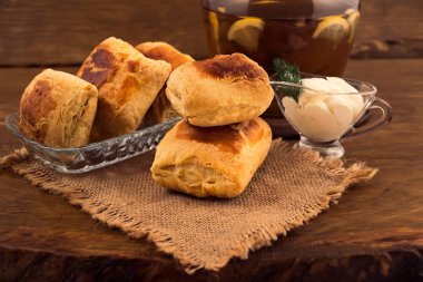 Pasta puf böreği peynirli doldurma, ekşi krema sosu dereotu, sapı ile tüm ahşap arka plan üzerinde bir cam sürahi limon dilimleri ile bitkisel çay.