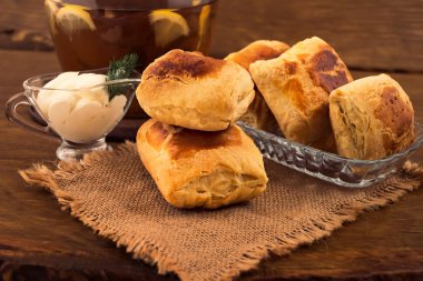 Kırmızı bir kabuk ile ev yapımı kekler koydu keten peçete ve bir cam levha, beyaz ekşi krema sos tekne, bir sürahi otlar çay limon dilimleri ile dereotu bir delikanlı ile.