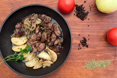 Yemekten elma ve soğan ile karaciğer yakınındaki küçük ahşap masa kara biber, Kuru ot, kırmızı tüm domates, biraz yukarıdan kızarmış.