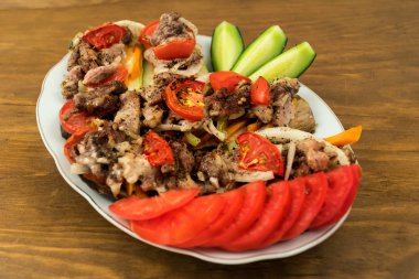 Bir porsiyon doldurulmuş fırında patlıcan et, domates, havuç ve soğan, dilimlenmiş taze domates, tüm Porselen tabakta, ahşap arka plan.