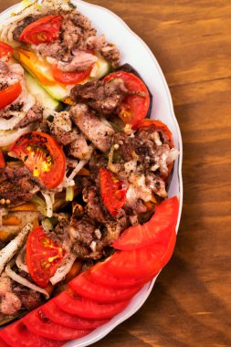 Kavrulmuş et parçaları ve dilim taze domates, dikey çerçeve, ahşap arka plan ile Sebze Güveç.
