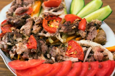 Kızarmış etli domates, soğan ve havuç yanında bir tabak içinde fırında patlıcan üzerine koydu, dilimlenmiş taze salatalık ve domates, yakın çekim.