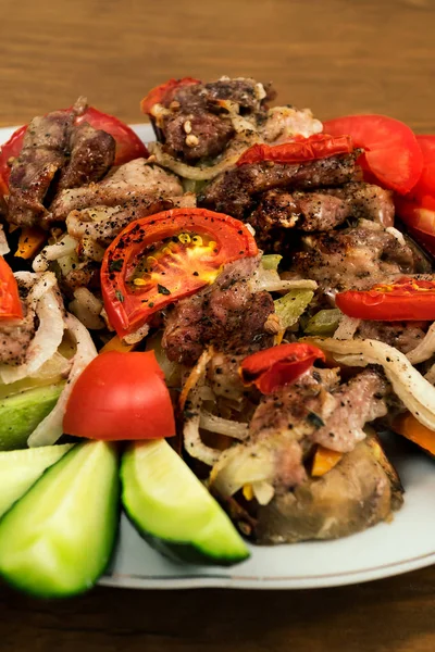 Fırında Etli Patlıcan, domates ve soğan, bir tabağa koydu ve dilimlenmiş salatalık ile dekore edilmiş.