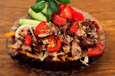 Fırında patlıcan domates, havuç ve soğan ile kavrulmuş et ile doldurulmuş bir bölümü, bir garnitür dilimlenmiş salatalık ve fesleğen yaprakları.