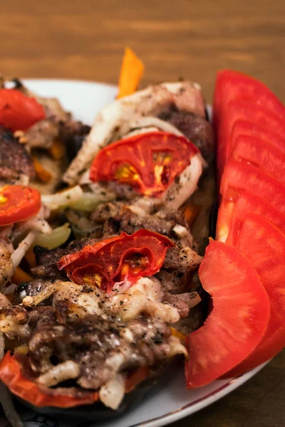 Fırında patlıcan dilim katmanları ile kavrulmuş et domates ve soğan, dilimlenmiş domates, dikey çerçeve, ahşap arka plan.