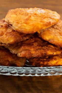 Yuvarlak ahşap arka plan üzerinde bir cam tabak peynirli bisküvi ince.